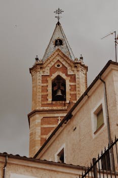 Low angle view of a Gothic-style bell tower in Cuenca, Spain with a moody sky.