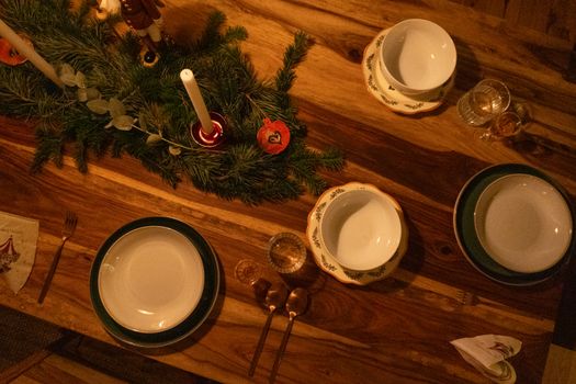 Warm and inviting Christmas table setup with candles and pine decor on wooden surface.