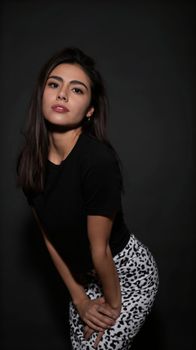 Stylish young woman posing in black top and patterned pants.