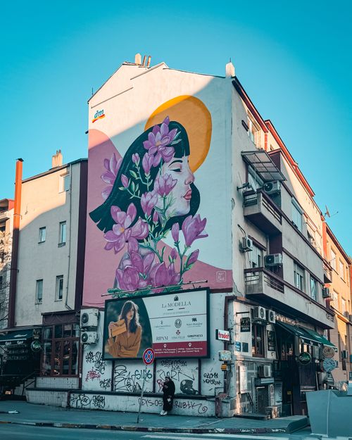 Free Vibrant street mural with floral motifs on a city building under clear skies. Stock Photo