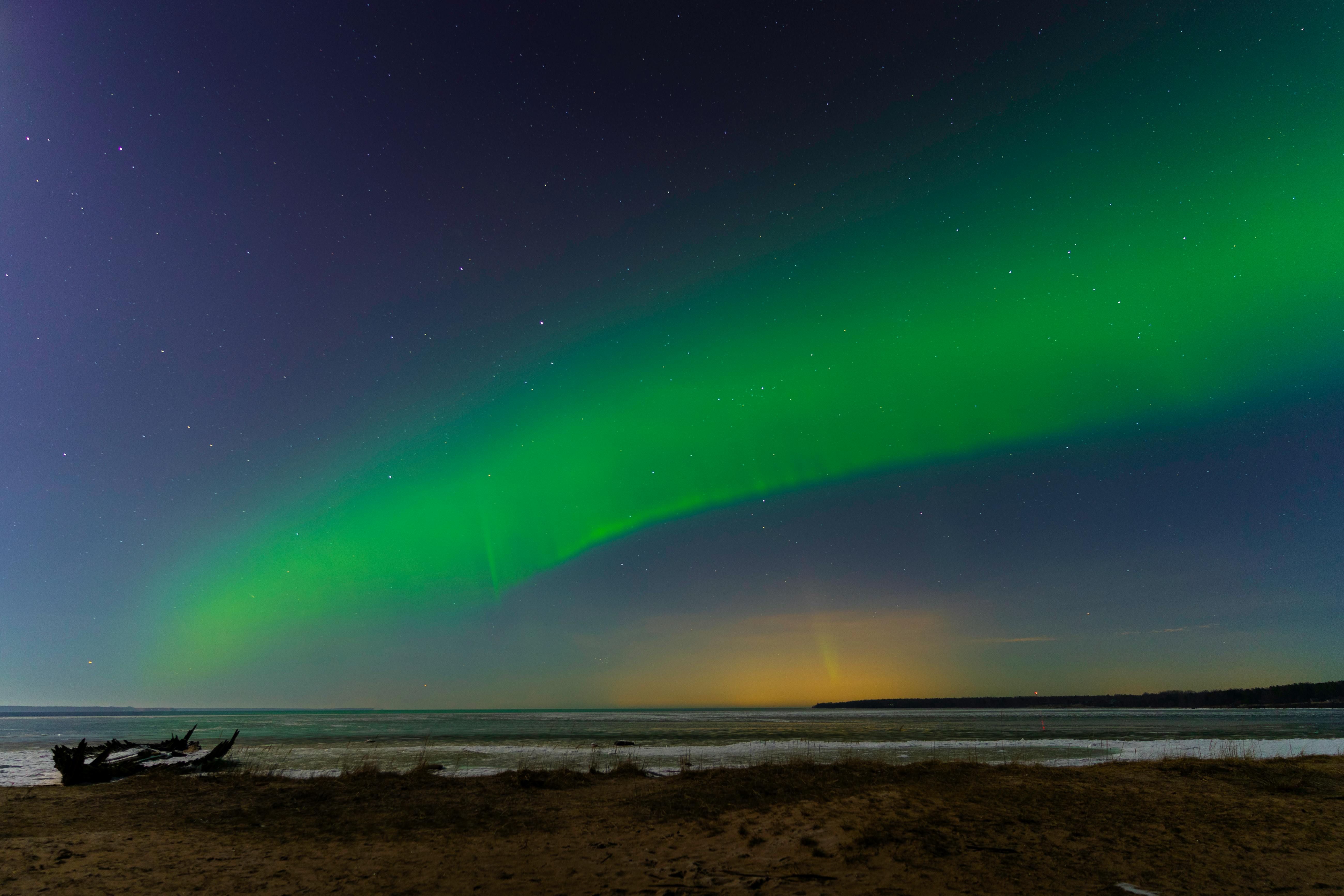 majestic northern lights over calm beach shoreline