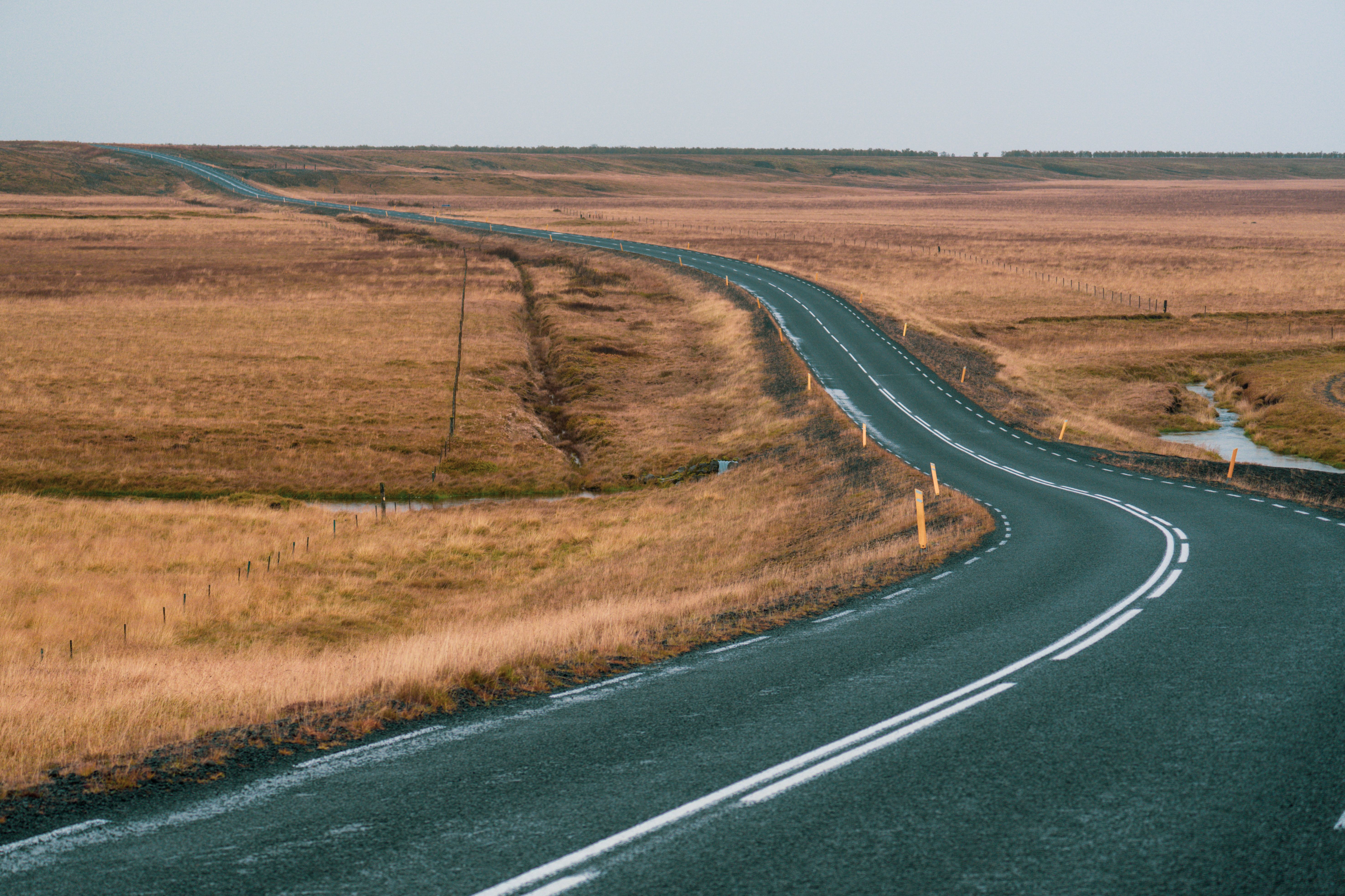 A scenic winding road through vast autumn plains under a clear sky, perfect for travel inspiration.