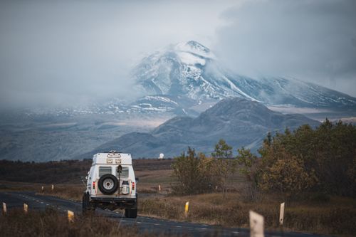 Free White SUV on rugged road with stunning snow-capped mountain view. Stock Photo