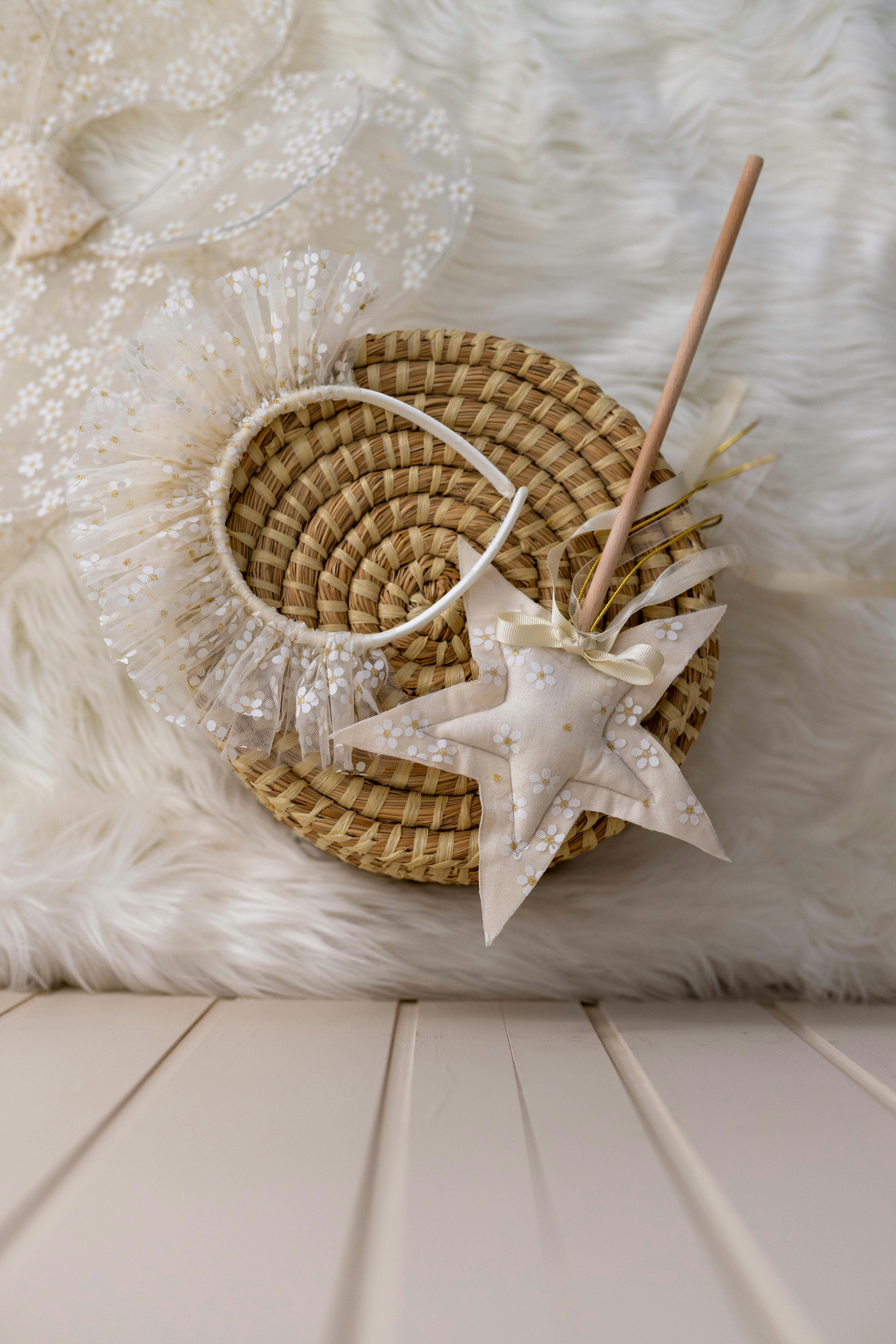 A delicate fairy princess costume with a lace crown, star wand, and basket on a fluffy white surface.
