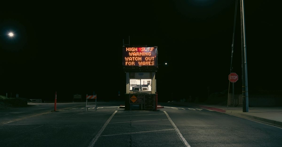 A high surf warning sign at night in Grover Beach, California. Atmospheric and moody lighting.