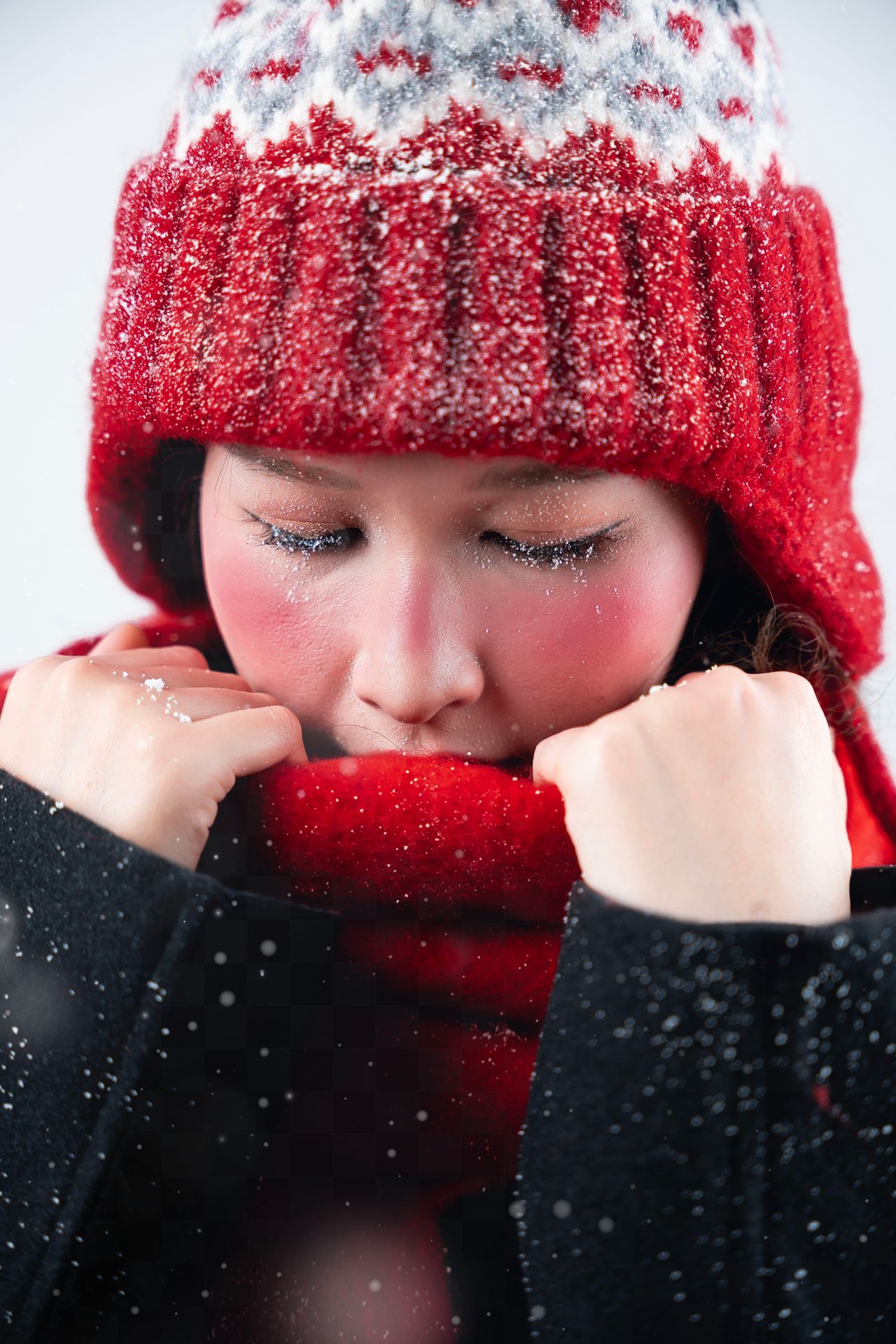 Woman in a red knit hat and red scarf in falling snow