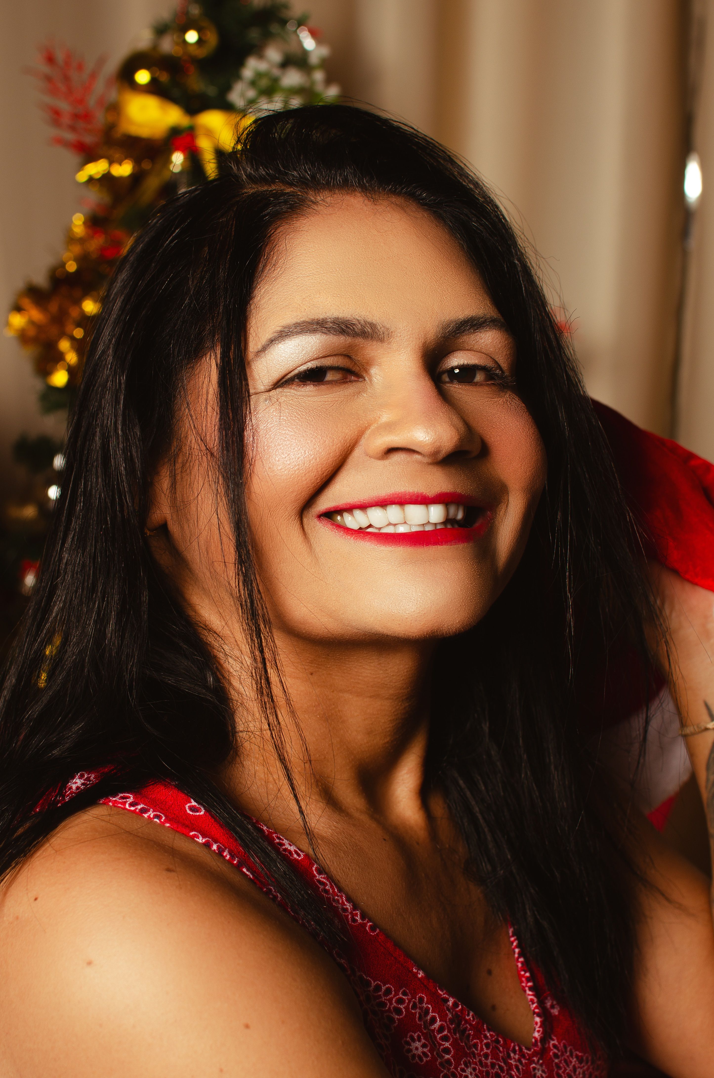 Smiling woman in festive attire enjoying Christmas indoors with decorations.