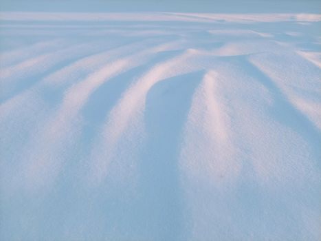 Peaceful snowy scene capturing snowdrifts under soft evening light in winter.