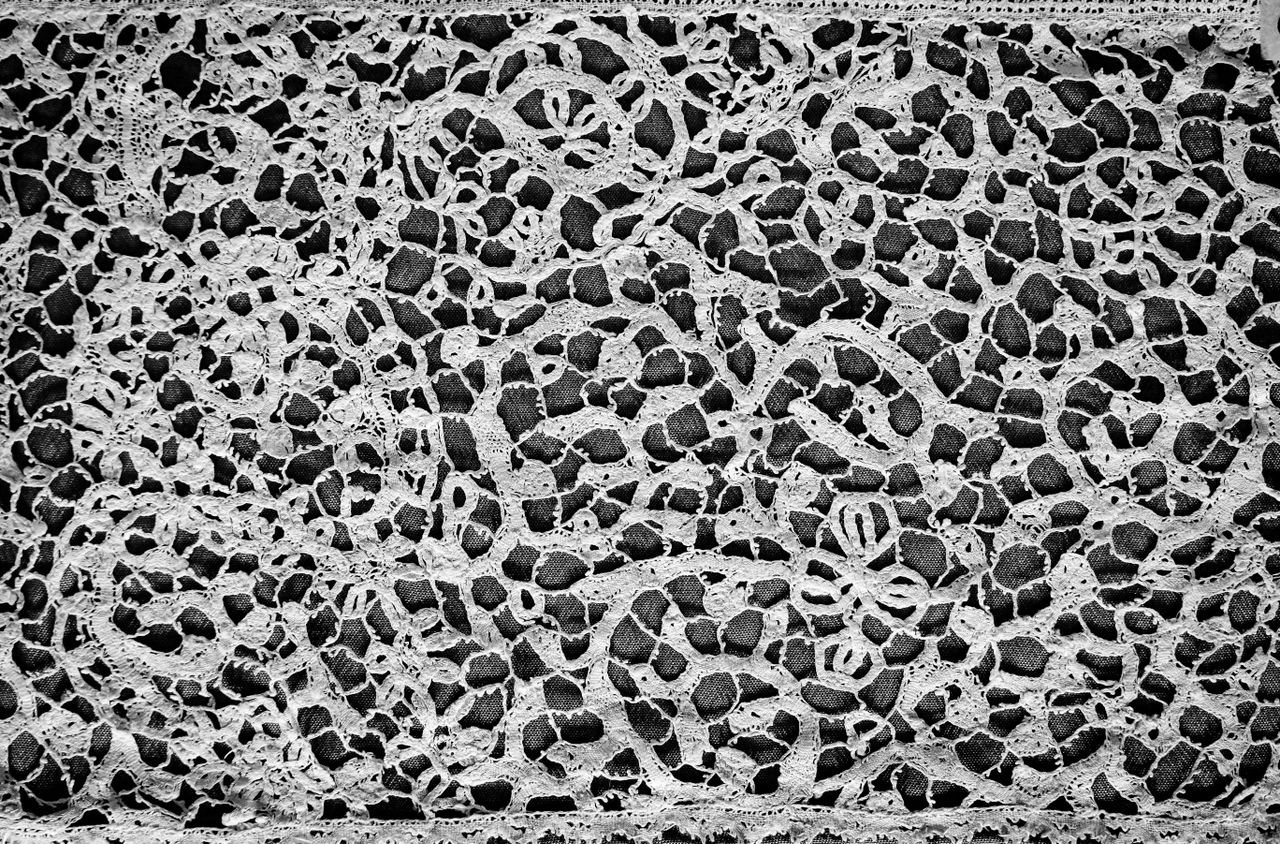 close up of an intricate lace fabric pattern in black and white showca