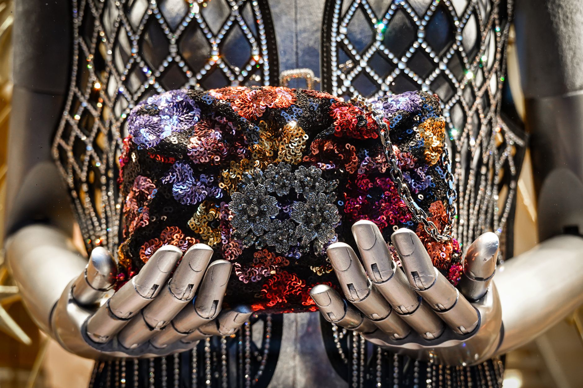A fashion mannequin showcases a colorful sequin handbag held gracefully by robotic hands. (Photo by Magda Ehlers on Pexels)