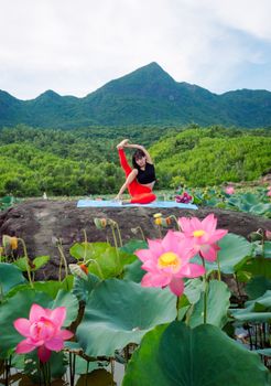 A woman practicing yoga surrounded by lotus flowers in Hội An, Vietnam.