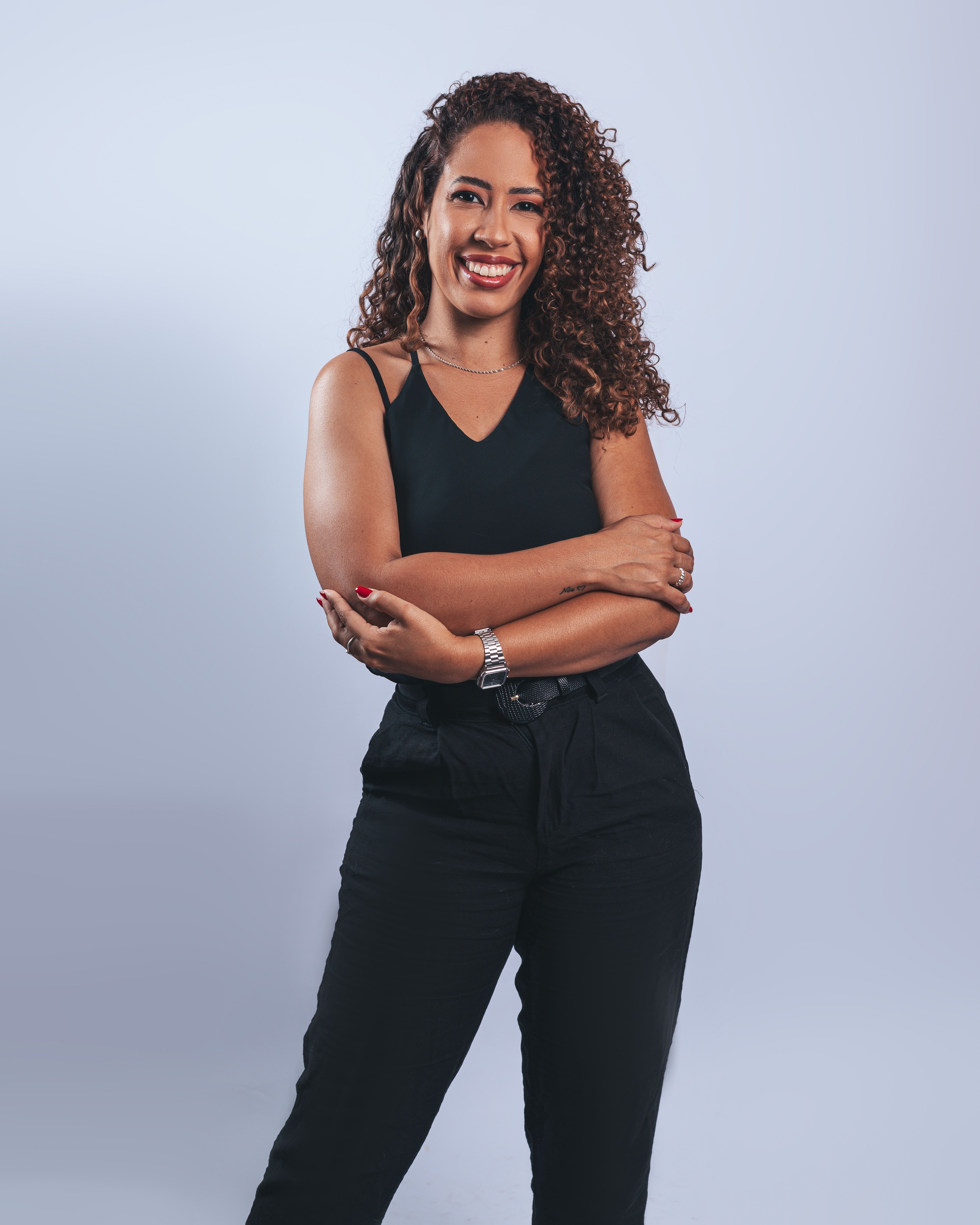 Smiling young woman in casual black attire posing confidently against a plain background.