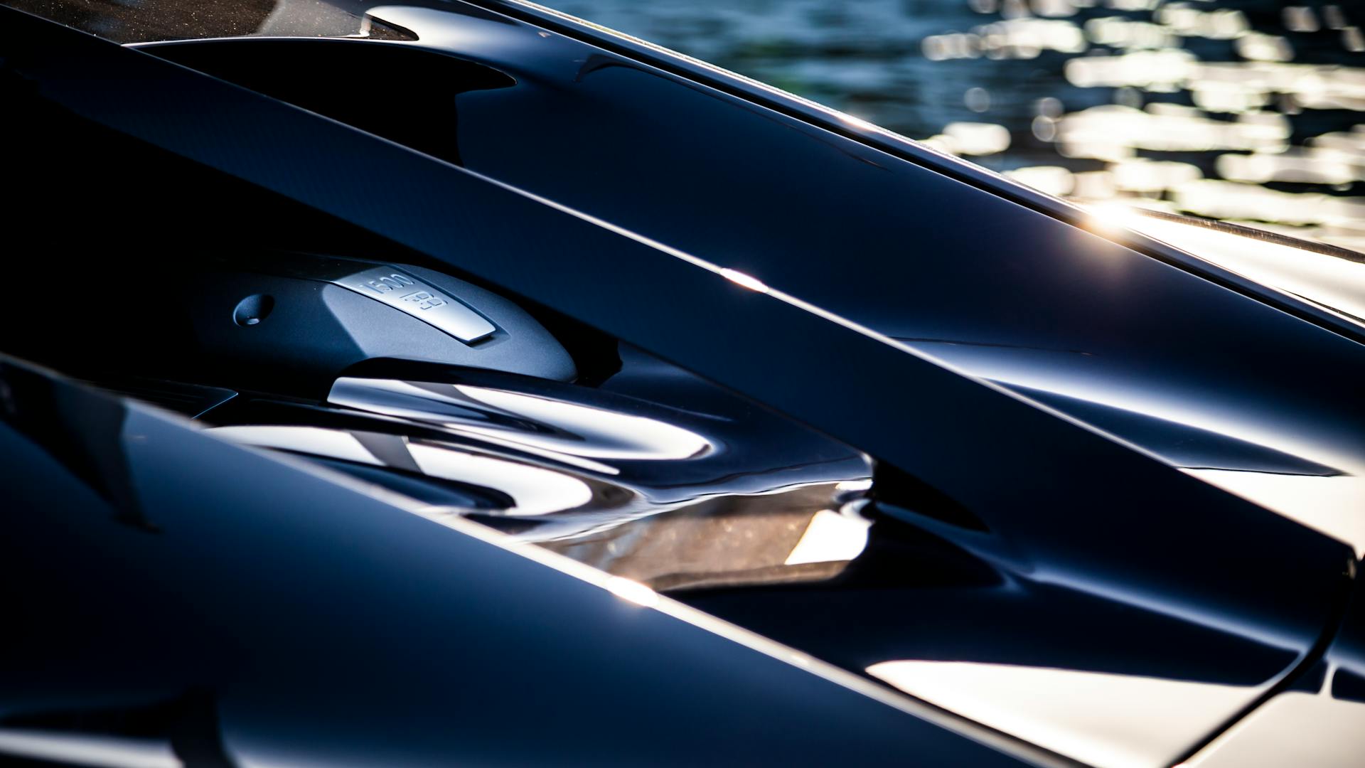 Detailed view of a luxury car engine with sleek reflections highlighting its polished elegance.