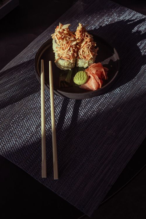 Free Artistic display of sushi rolls and chopsticks with shadows creating a moody ambiance. Stock Photo