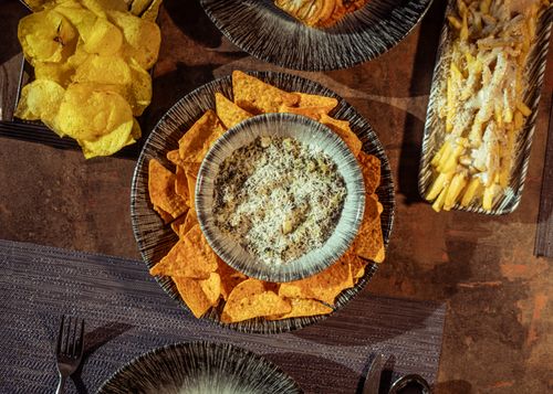 Free Aerial view of chips, nachos with dip, and pasta on a rustic table setting. Stock Photo