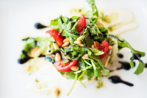 Free A vibrant arugula salad with cherry tomatoes, pine nuts, and balsamic glaze. Stock Photo