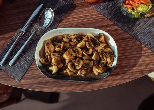 Free A plate of sautéed mushrooms garnished with herbs, served on a stylish dining setup. Stock Photo