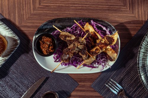 Free Delicious grilled skewers on cabbage served with a dipping sauce, offering a taste of Middle Eastern cuisine. Stock Photo