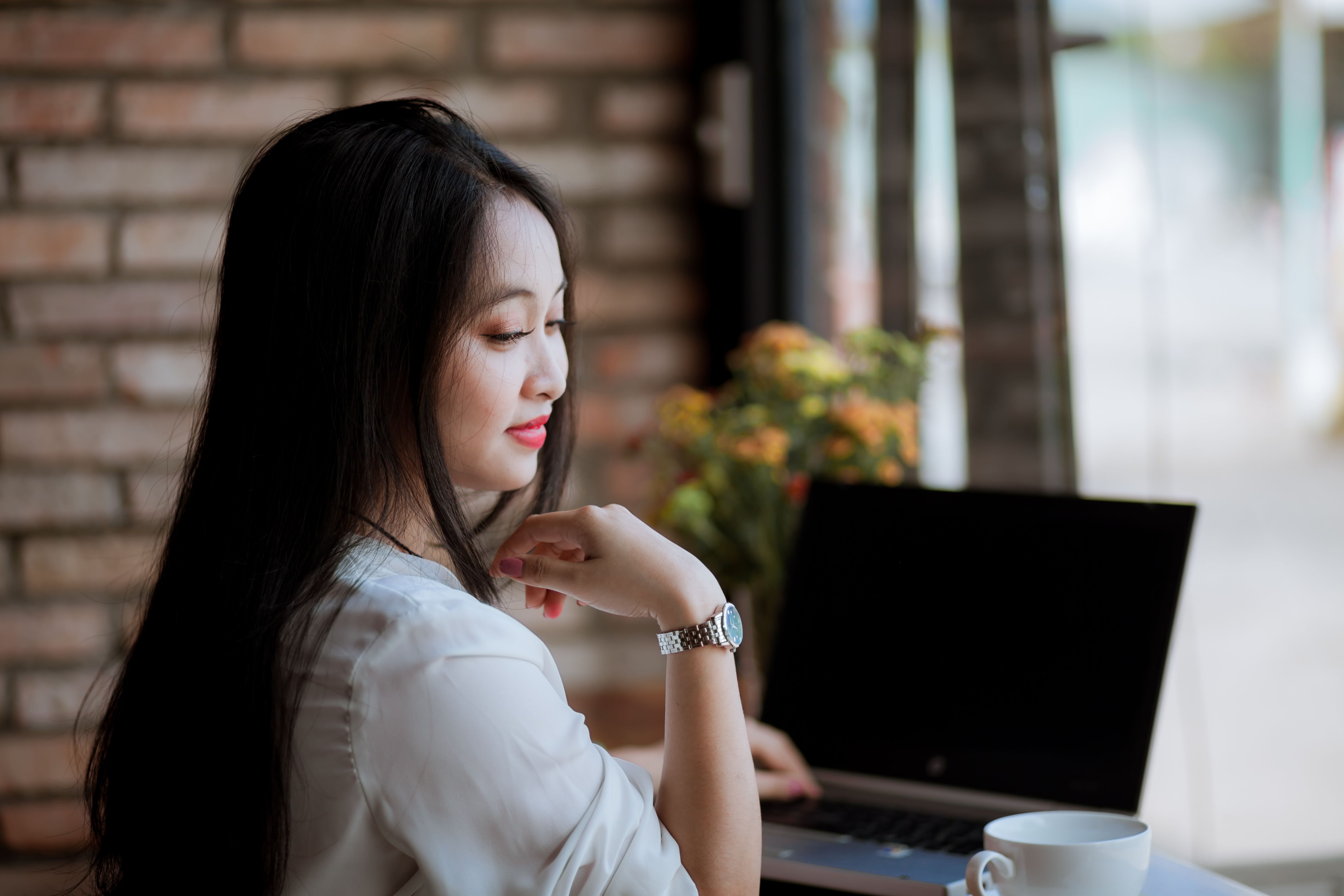 A young woman works on her laptop in a cozy cafe with a cup of coffee, showcasing a relaxed and productive atmosphere.