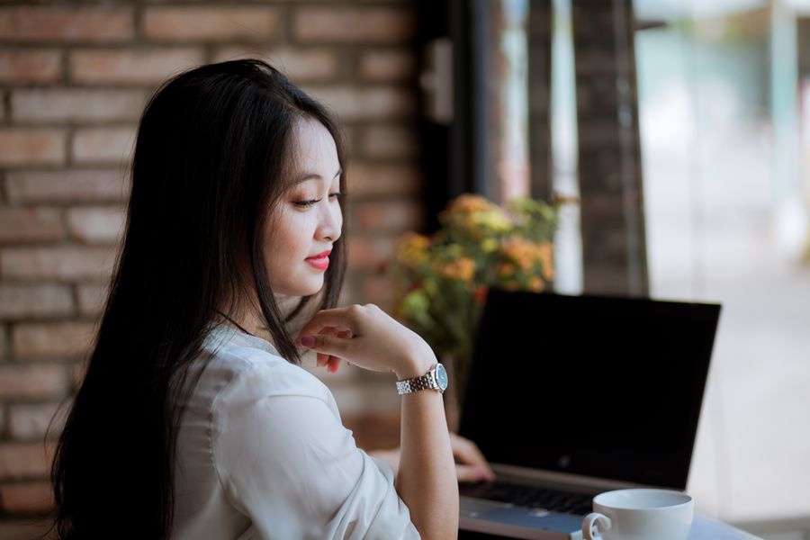 A young woman works on her laptop in a cozy cafe with a cup of coffee, showcasing a relaxed and productive atmosphere.