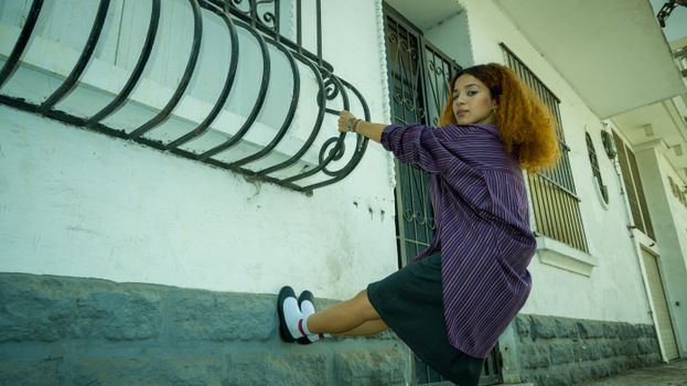 Young woman in striped shirt posing playfully outdoors in urban Moroccan street scene.