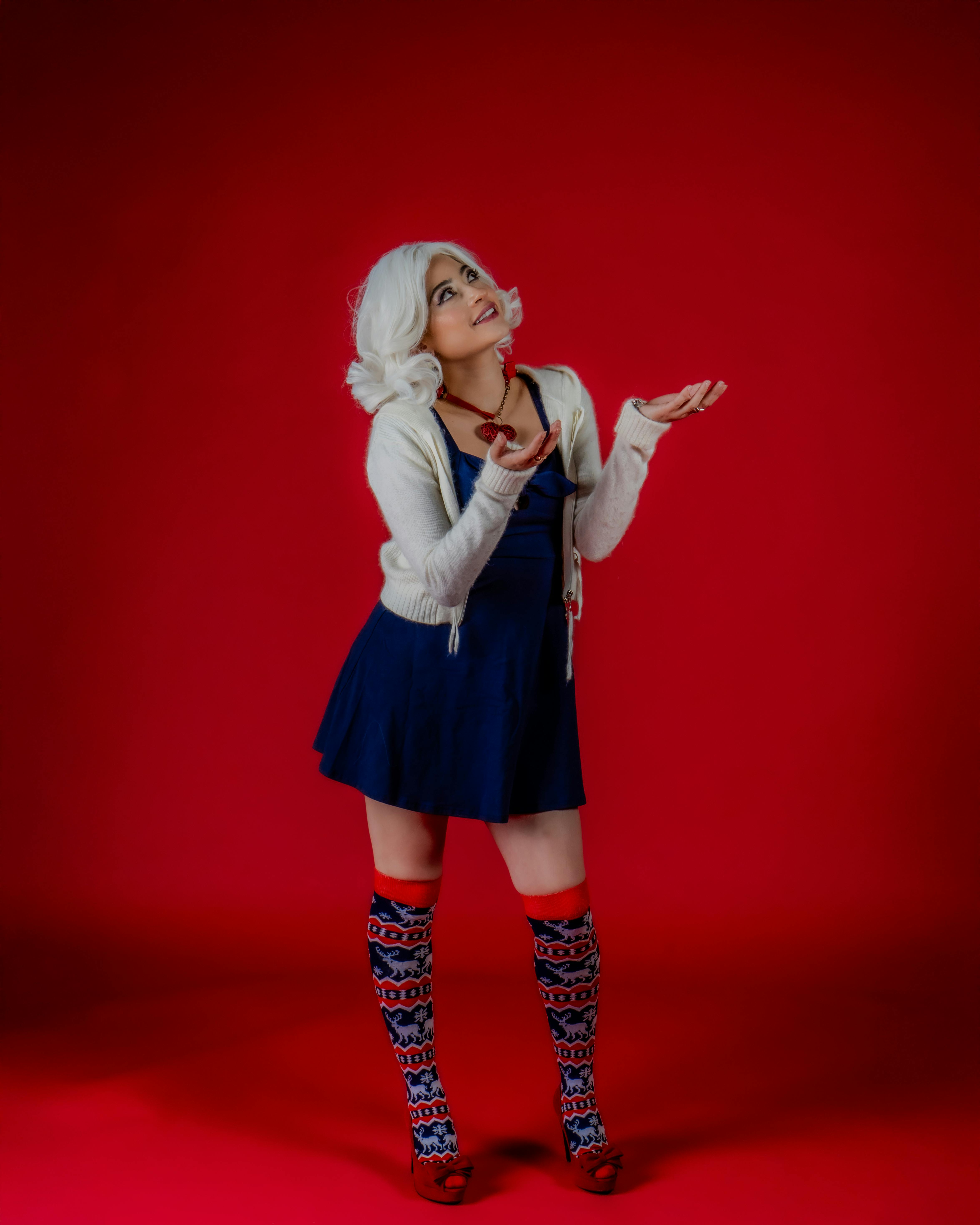 Gratis Mujer con cabello blanco en traje festivo sobre un fondo rojo, mirando hacia arriba. Foto de stock