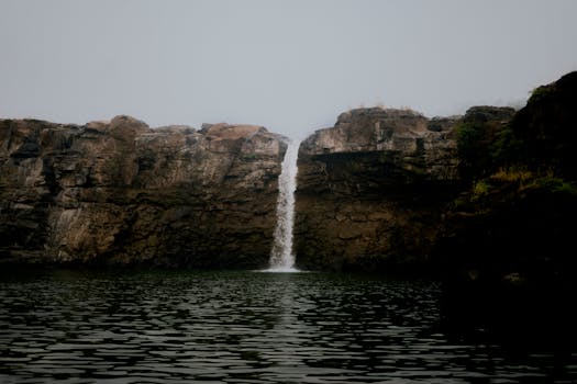 A serene waterfall cascading down rocky cliffs in India, surrounded by lush greenery.