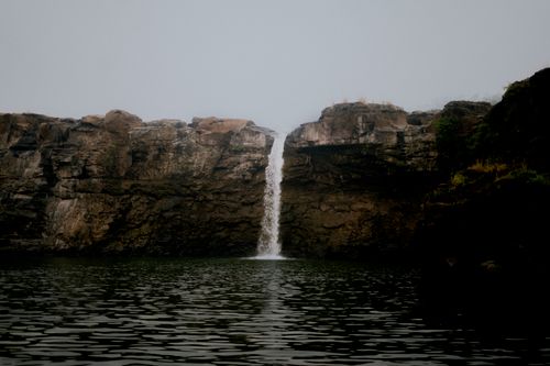 Free A serene waterfall cascading down rocky cliffs in India, surrounded by lush greenery. Stock Photo