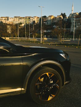 A sleek luxury car parked with a cityscape backdrop during sunset, highlighting urban elegance.