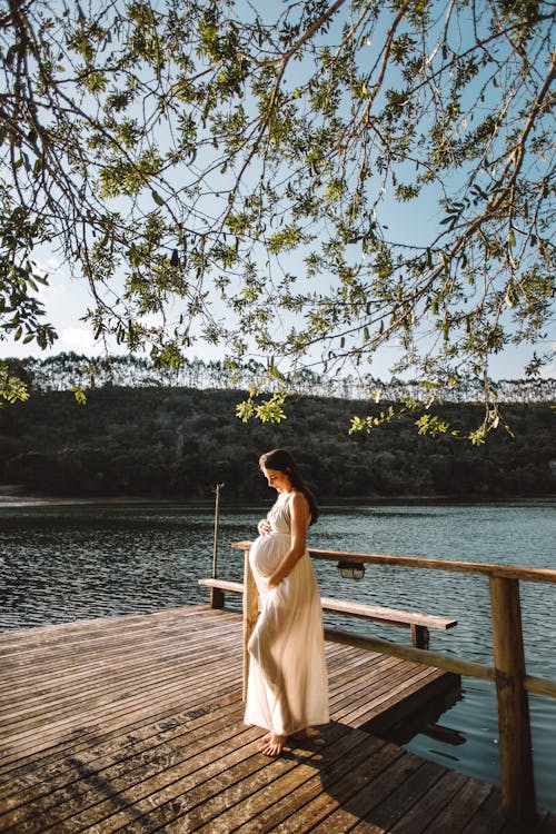 Photo Of Pregnant Woman Standing On Dock 