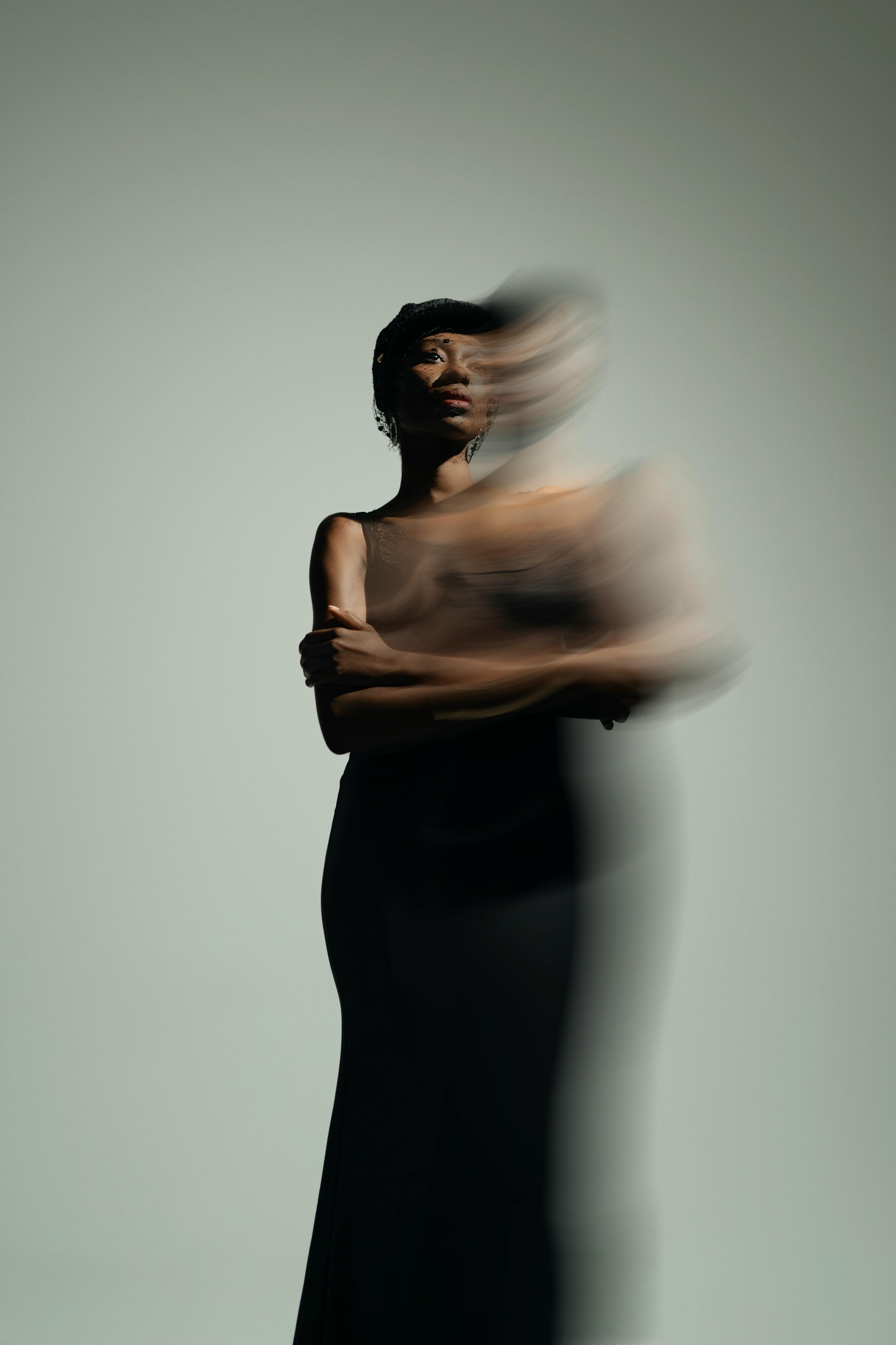 Model in a blurred motion portrait wearing a sleek black dress, creating an artistic and moody composition.