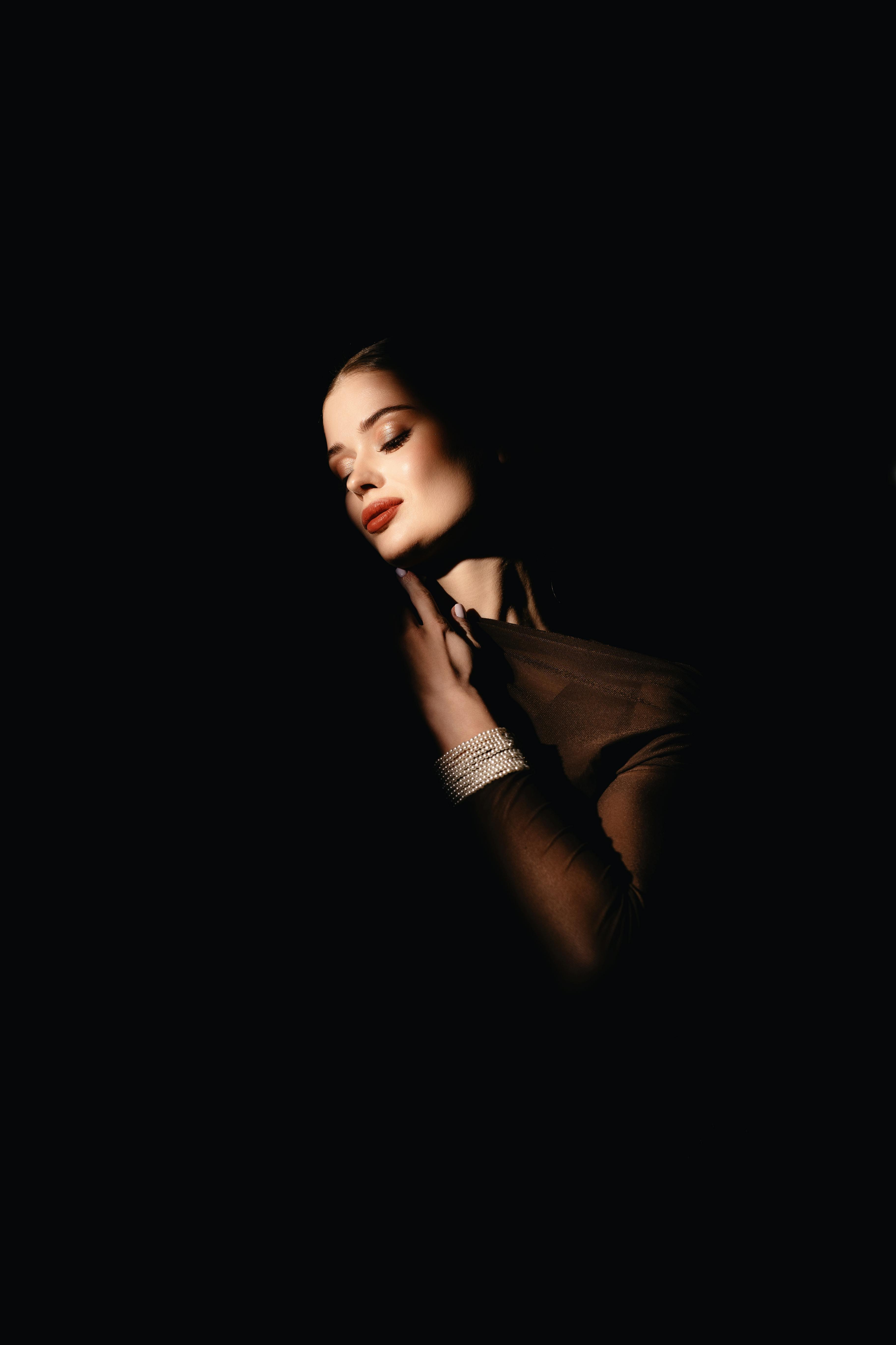 Bezpłatne Dramatyczny portret studyjny prezentujący olśniewającą modelkę o szykownym stylu i wyrafinowanym oświetleniu. Zdjęcie z galerii