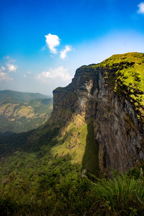 Free A breathtaking view of a towering cliff surrounded by verdant landscapes in Balige, India, under a clear blue sky. Stock Photo