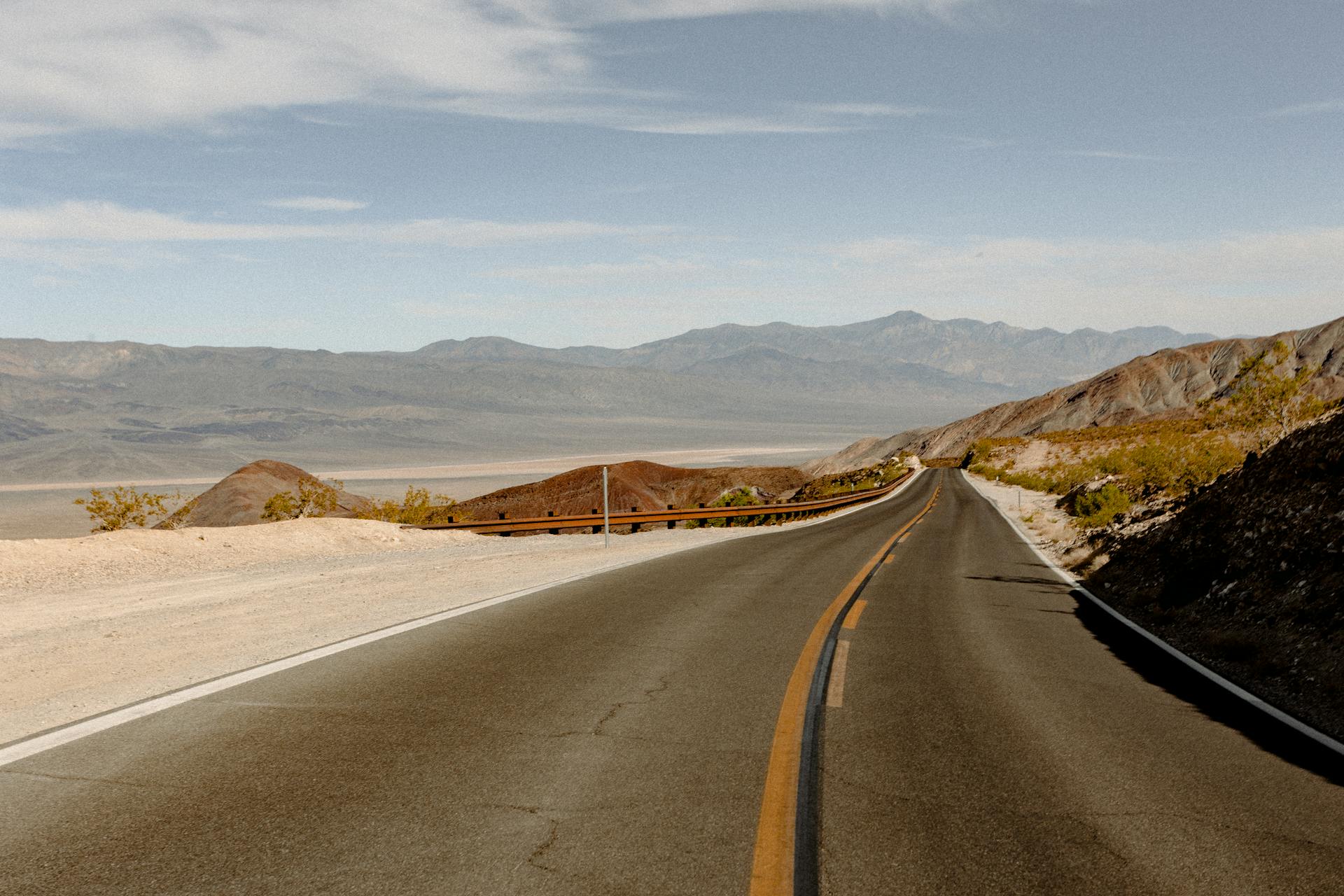 Explore the open road through a desert landscape with distant mountains and clear skies.