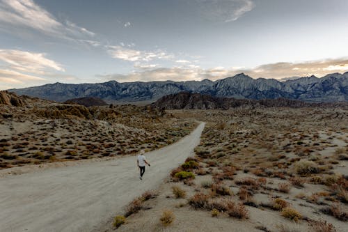 Free Person Wearing White Shirt Walking on Dirt Road Stock Photo