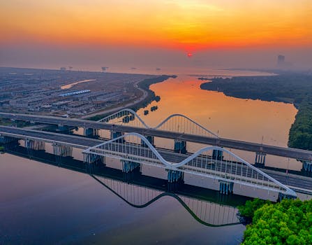 日出时分，印度尼西亚雅加达一座桥梁的鸟瞰图倒映在平静的海水中，景象令人惊叹