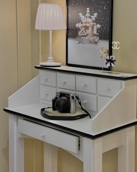 A stylish white desk setup featuring a camera and chic decor in a modern interior setting.