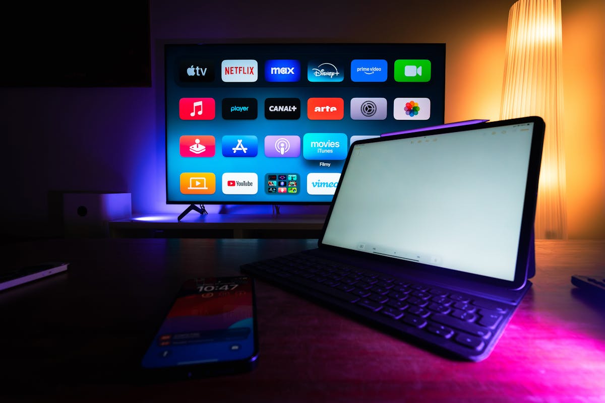 TV con app di streaming visibili, tablet e smartphone appoggiati su tavolo