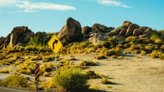 蔚蓝的天空下，沙漠景观中的路标旁，矗立着巨石和灌木