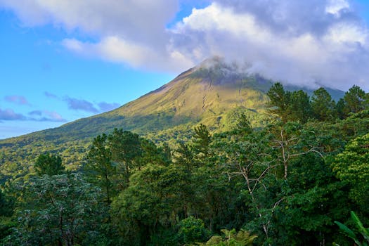 Breathtaking view of a lush green landscape with a majestic volcanic mountain under a cloudy sky.