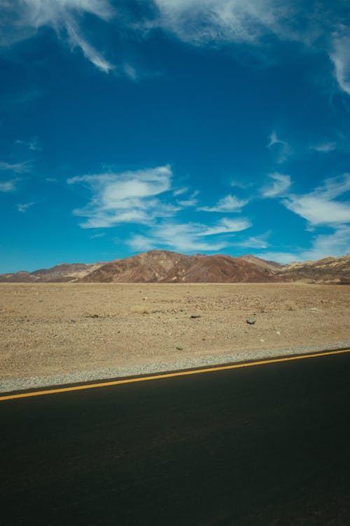 Free Highway Across Mountain Range Under Blue Sky Stock Photo