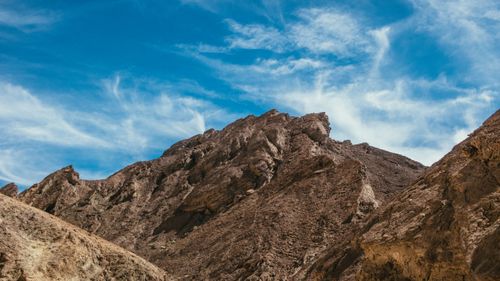 Free Panoramic view of a rocky mountain with a bright blue sky and wispy clouds. Stock Photo