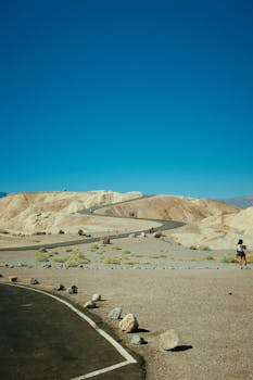 沙漠道路蜿蜒穿过干旱的山丘，天空充满活力，风景迷人