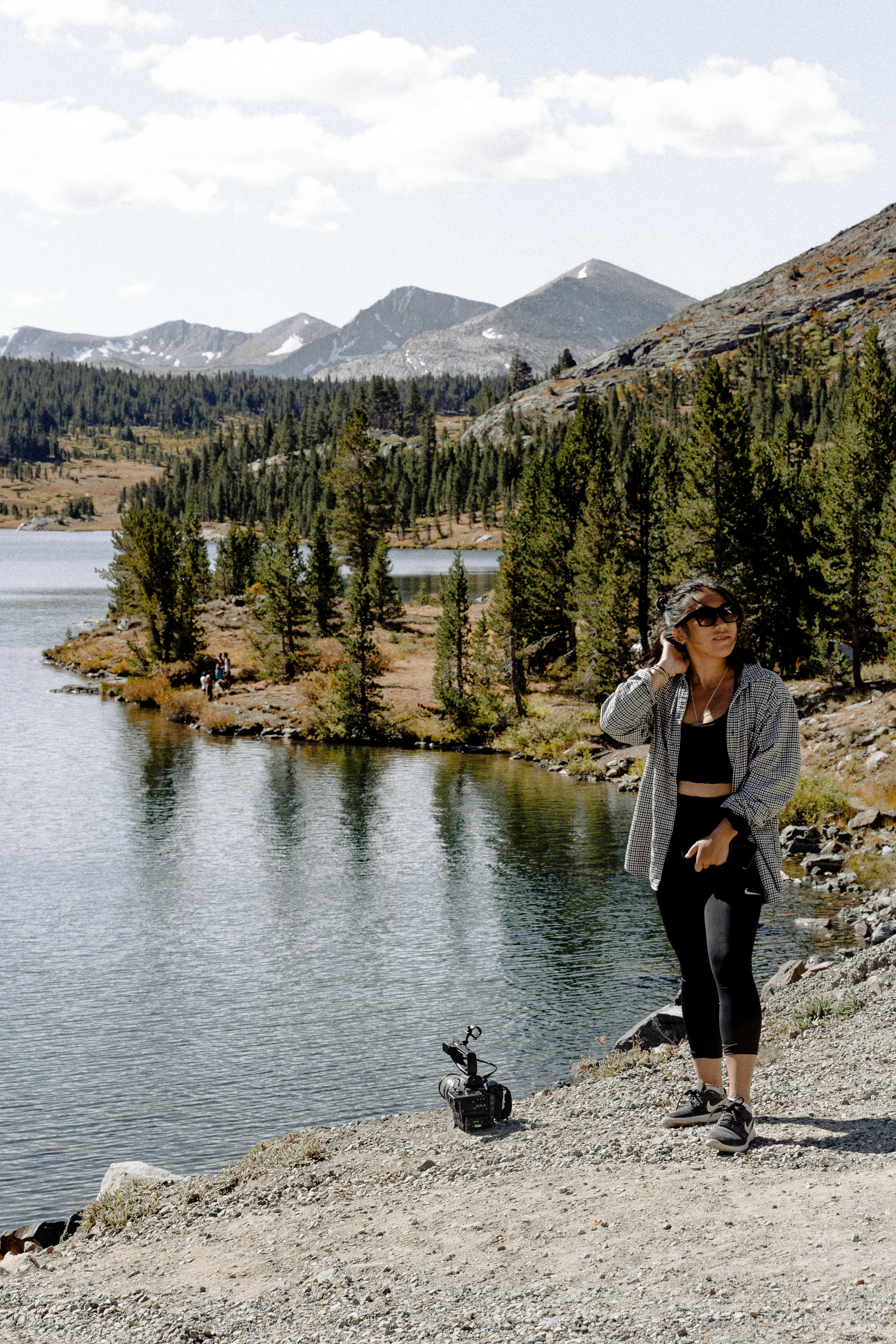 一名妇女在山间湖泊旁享受平静的徒步旅行，四周被大自然环绕