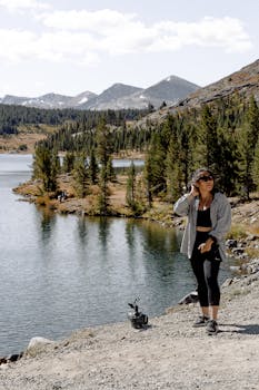 一名妇女在山间湖泊旁享受平静的徒步旅行，四周被大自然环绕