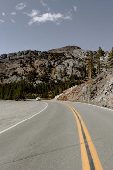 一条蜿蜒的道路穿过岩石山脉，在晴朗的天空下，非常适合旅行主题