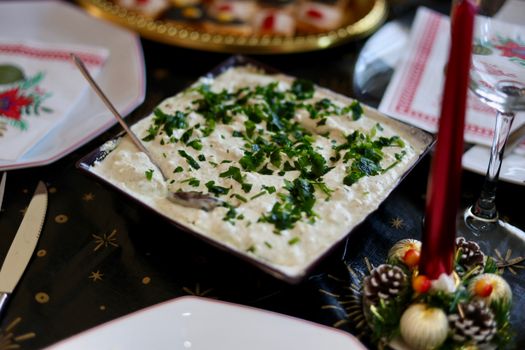 Elegant holiday table setting with a creamy cheese dip garnished with fresh herbs.