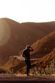 日落时分，蜿蜒的山路上，一个人行走的剪影展现了宁静的自然之美