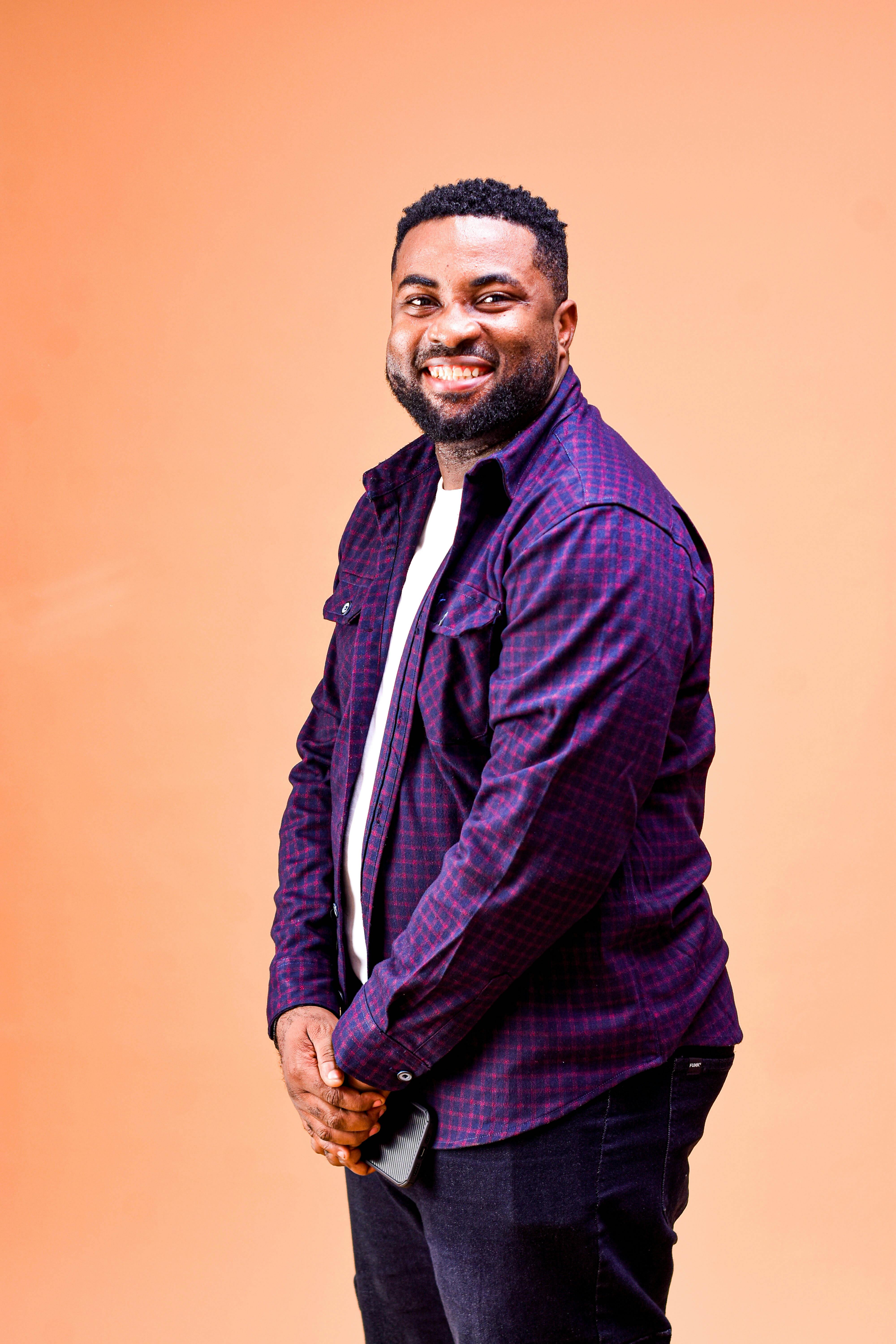 Cheerful man with a big smile posing against a vibrant orange backdrop.