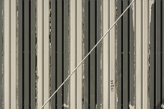 Close-up of a striped metal wall with a diagonal rope creating a modern abstract pattern.